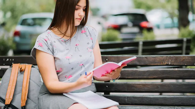 "Mother reading Bible app on phone while waiting in school pickup car line, showing practical way busy parents can fit in devotion time"