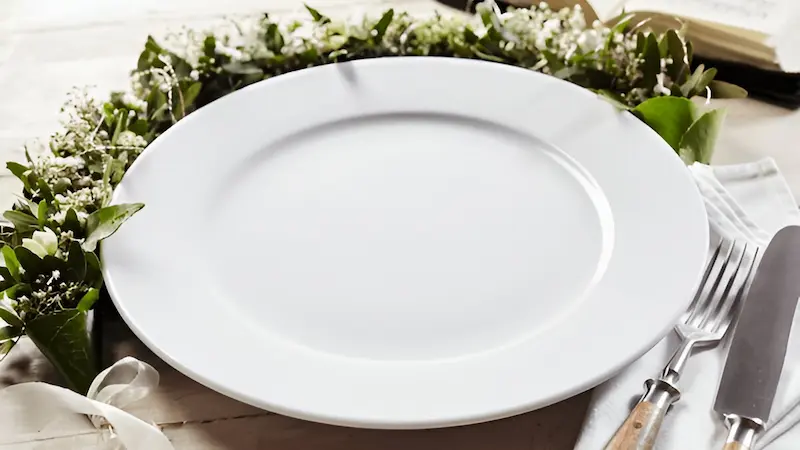 Open Bible next to an empty plate”


