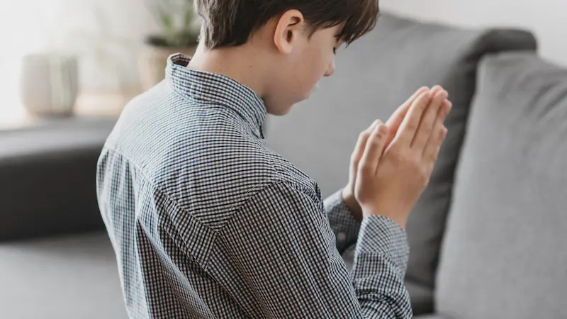 Person kneeling in prayer with hands clasped, symbolizing devotion and reliance on God’s strength.