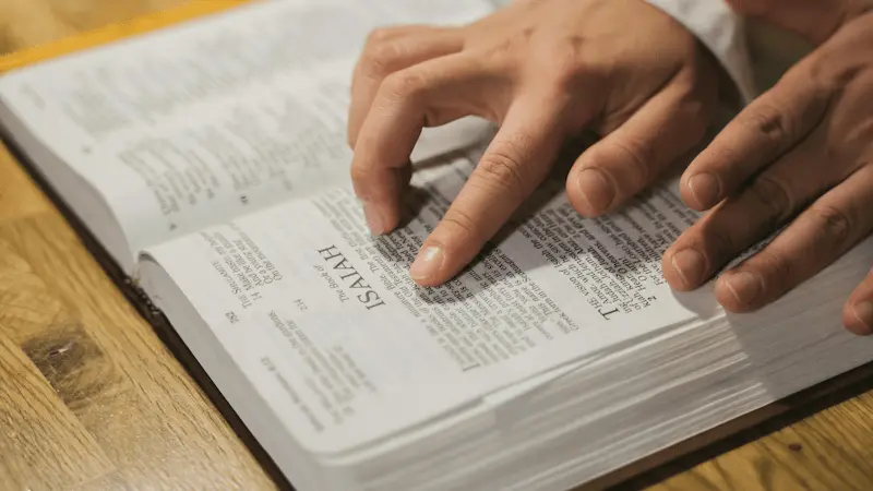Close up of an open Bible showing Isaiah chapter 14, with verses 12-15 highlighted in yellow.