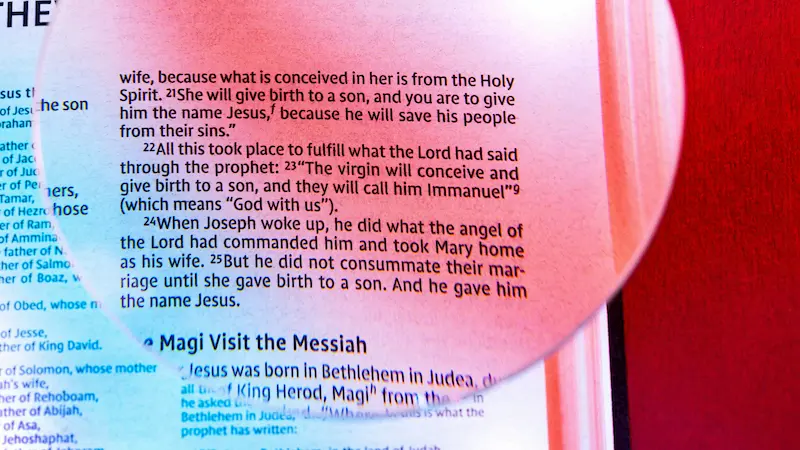 A close-up of an open Bible with a verse highlighted: "When Joseph woke up, he did what the angel of the Lord had commanded him and took mary home as his wife"