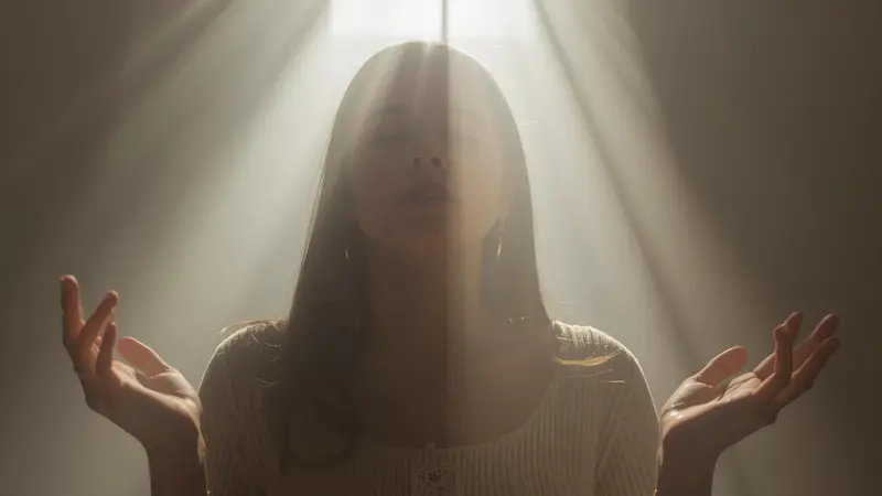 Person in prayer with open hands, symbolizing surrender to Christ.