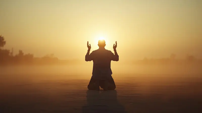 Person kneeling in prayer at dawn symbolizing repentance.