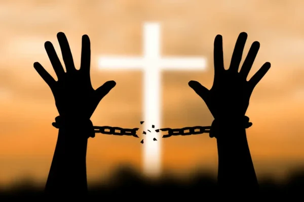 Hand breaking free from metal chains, symbolizing spiritual freedom through Christ, referencing John 8:36.