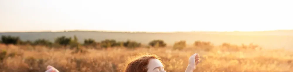 Joyful person lifting arms toward radiant sunlight in a vibrant landscape, symbolizing spiritual fulfillment in Christ.