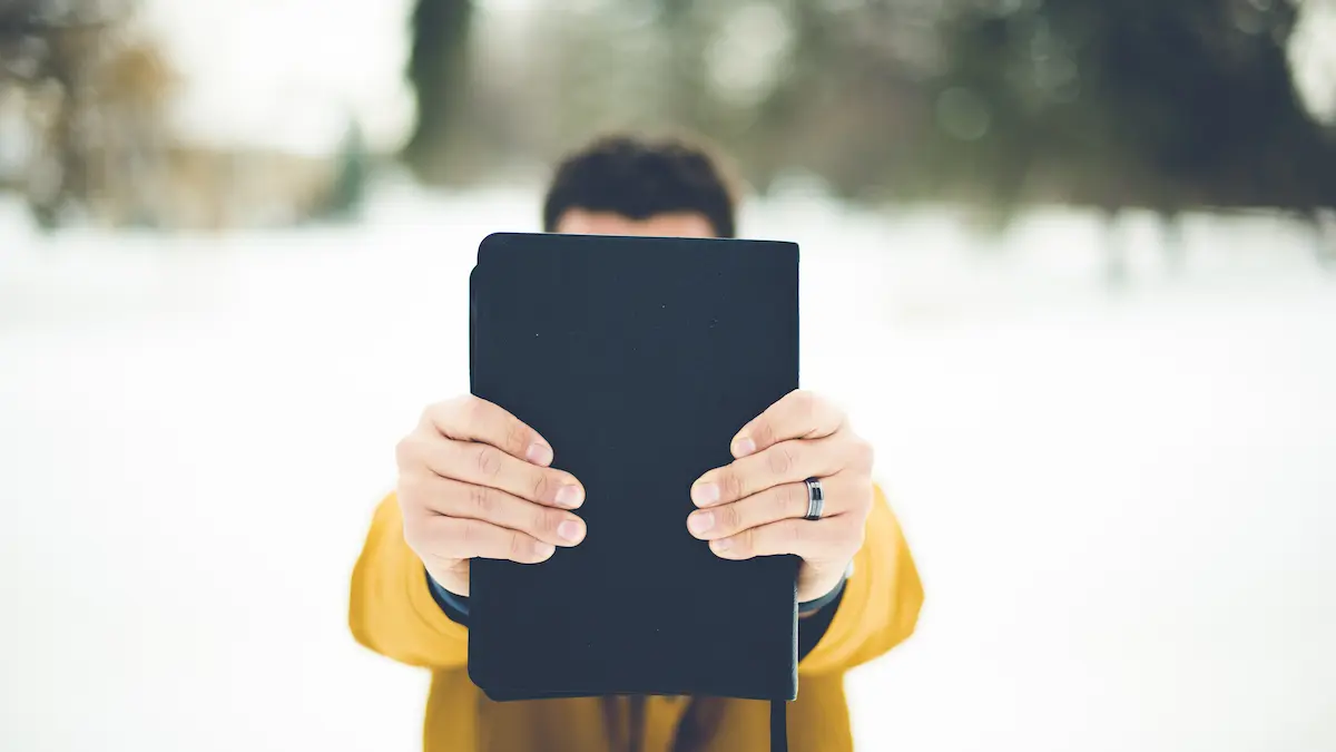 Bible raised against storm as a symbol of faith.