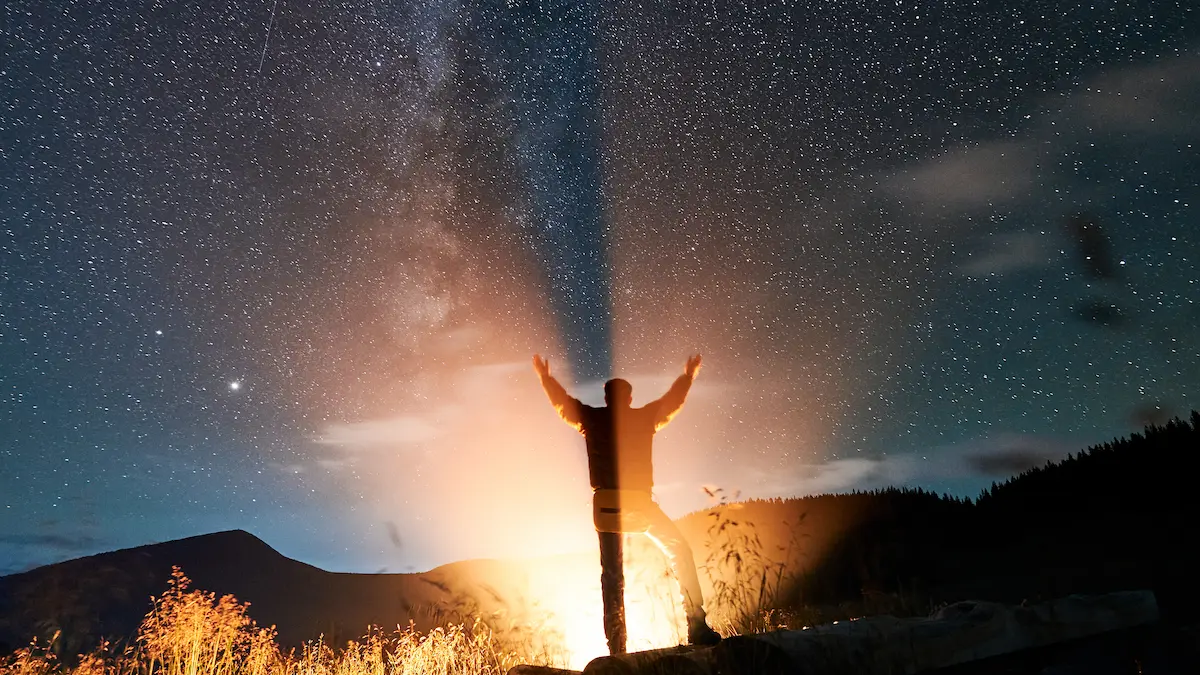 Christian lifting hands in prayer under starry night sky