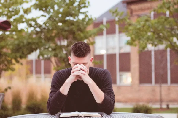 Person kneeling in prayer with Bible
